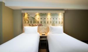 two beds in a room with a picture of a building at President Hotel in London +142 photos