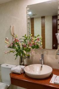 a bathroom with a sink and a vase of flowers at Sree Parijatha Grand in Bengaluru