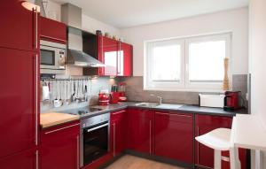 a red kitchen with red cabinets and a window at Villa Kunterbunt in Olpenitz +13 photos