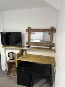 a wooden desk with a television and a chair at The Pier Hotel in Aberystwyth