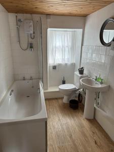 a bathroom with a tub and a toilet and a sink at The Pier Hotel in Aberystwyth +10 photos