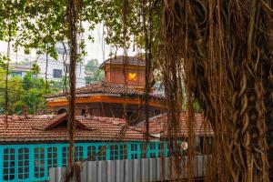 a blue building with a brown roof and a tree at Madpackers Goa Anjuna - Bar in Anjuna
