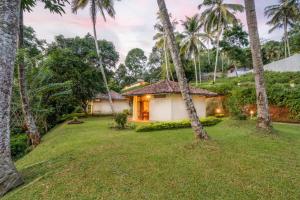 a house in the middle of a yard with palm trees at Athulya Villas, Kandy in Kadugannawa