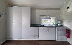 a kitchen with white cabinets and a sink at Selje Camping - Hytte Nr 4 in Selje