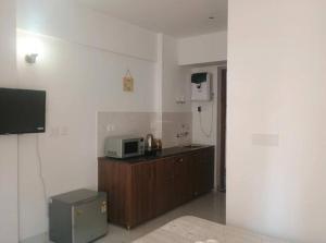 a kitchen with a microwave and a counter with a tv at ATS Grand Casa 02 in Greater Noida