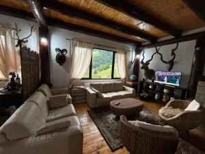 a living room with white couches and a tv at A Hunter's Lodge in Dâmbovicioara