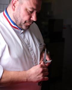 a man in a chef uniform holding a pair of scissors at La Villa Mauresque in Saint-Raphaël
