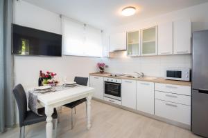 a kitchen with white cabinets and a table with chairs at Apartment Sandra with balcony in Split