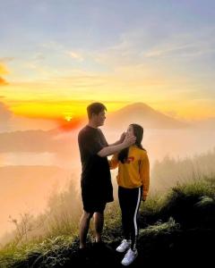a man and a woman standing on top of a mountain at Mount Batur Sunrise and Sunset Camping in Bangli
