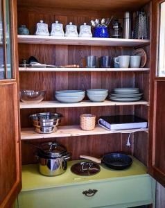 a shelf with plates and bowls and dishes on it at Bienenwagen Weitblick, Kamin, Sauna ganzjährig nutzbar in Dargun