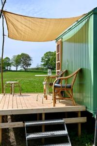 two chairs sitting on a deck with a green building at Bienenwagen Weitblick, Kamin, Sauna ganzjährig nutzbar in Dargun