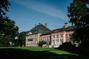 a large brick building with a green lawn at Schloss Karow in Plau am See