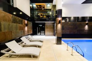 eine Hotellobby mit Pool und Liegestühlen in der Unterkunft Arena Hotel Spa & Wellness in Tychy