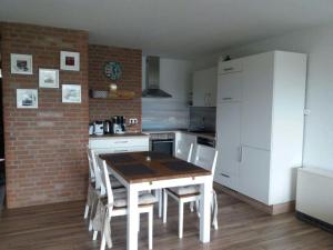 a kitchen with a wooden table and a white refrigerator at Ferienwohnung Nordseetraum in Tossenserdeich