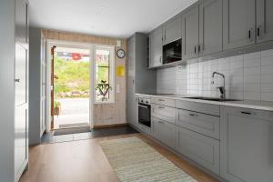a kitchen with white cabinets and a sink and a door at Tällberg, utsikt över Siljan in Leksand +14 photos