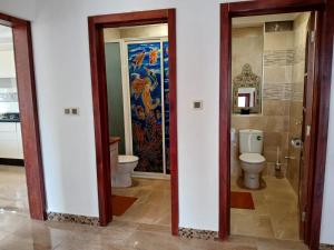 a bathroom with a toilet and a painting on the wall at Découvrez ce havre de paix in Imi Ouaddar +10 photos