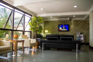 - un salon avec des canapés et une télévision murale dans l'établissement Guará Inn Flat Service, à Guaratinguetá