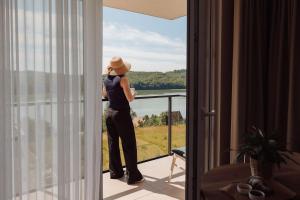 a woman standing on a balcony looking out at the water at Jezioranka Apartamenty in Ostrzyce
