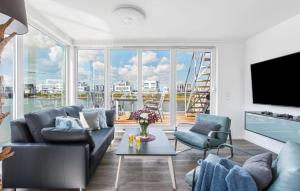 een woonkamer met een bank, stoelen en een tv bij Sunseeker in Olpenitz