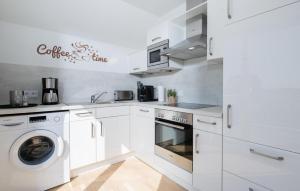 a kitchen with white cabinets and a washer and dryer at Windrose in Olpenitz +14 photos