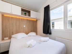 a bedroom with a large white bed with towels on it at Chalet in Middelkerke near the Beach in Middelkerke