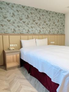 a bedroom with a bed and a floral wallpaper at Toongmao Hotel Kaohsiung in Kaohsiung