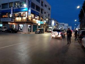 a man walking down a city street at night at Appartement Vacances Nador in Nador