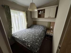 a small bedroom with a bed and a window at Family 3 Bedroom Caravan at Heacham Beach in Hunstanton +14 photos