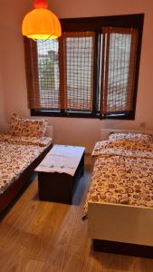 a room with two beds and a table and windows at Makedonium 1 in Struga