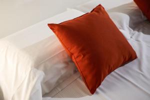 an orange pillow sitting on a white bed at De Bardi - Beautiful Home near Ponte Vecchio in Florence