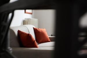 a white couch with two orange pillows on it at De Bardi - Beautiful Home near Ponte Vecchio in Florence