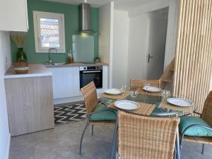 a kitchen with a table and chairs and a kitchen with green at Les planètes du port in Marseillan