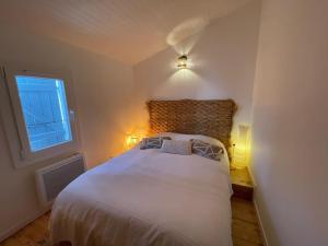 a bedroom with a white bed and a window at Les planètes du port in Marseillan