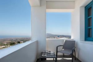 a chair sitting on a balcony with a window at Aeifos Boutique Hotel in Imerovigli