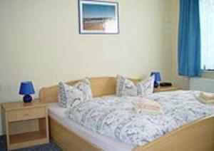 a bedroom with a bed and a night stand with a blue lamp at Haus Dornröschen in Koserow