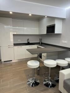 una cucina con mobili bianchi e un bancone con sgabelli di Appartamento Esclusivo in Monaco Palace Josephine a Beausoleil