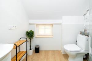a white bathroom with a toilet and a window at VacationClub - Staszica 36 Apartament 7 in Karpacz +8 photos