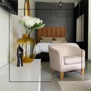 a bedroom with a vase with white flowers and a chair at Cosy apt 5min to Sandton City 14 in Johannesburg