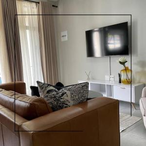 a living room with a brown leather couch and a television at Cosy apt 5min to Sandton City 14 in Johannesburg