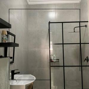 a bathroom with a glass shower and a sink at Cosy apt 5min to Sandton City 14 in Johannesburg