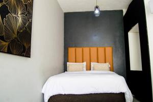 a bedroom with a bed with an orange headboard at Cosy apt 5min to Sandton City 14 in Johannesburg +20 photos