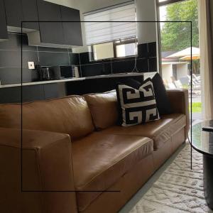 a brown leather couch in a living room at Cosy apt 5min to Sandton City 14 in Johannesburg