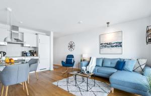 ein Wohnzimmer mit einer blauen Couch und einer Küche in der Unterkunft Meerleben in Olpenitz