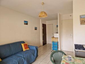 salon z niebieską kanapą i stołem w obiekcie Appartement avec piscine et parking, proche des commerces - FR-1-387-189 w mieście Marseillan