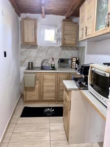 una piccola cucina con armadi in legno e lavandino di Glykeraki's House a Nea Kalikratia