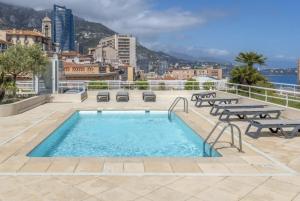 una piscina sul tetto di un edificio con panchine di Appartamento Esclusivo in Monaco Palace Josephine a Beausoleil