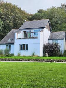 a white house sitting on top of a lush green field at Cornwall Truro Falmouth cottage in Perranwell