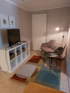 a living room with a couch and a tv at Flora Dekor gästgård, Lenagården in Alingsås