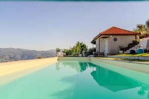a swimming pool with blue water in front of a house at Paradise Farm with pool and jacuzzi in Douro in Santa Cruz do Douro