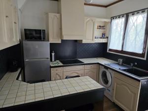 a kitchen with white cabinets and a washer and dryer at Maison Paris, Vallée Village, Disney & Astérix in Chelles